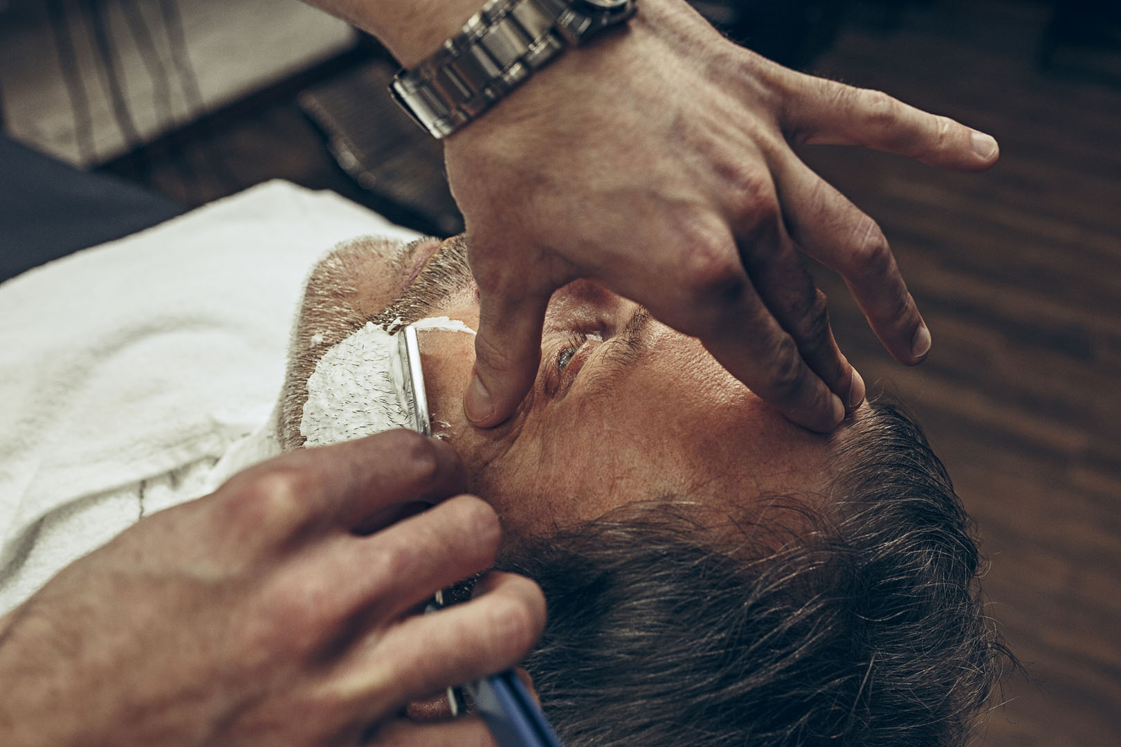 Close up side top view handsome senior bearded caucasian man getting beard grooming in modern barbershop.