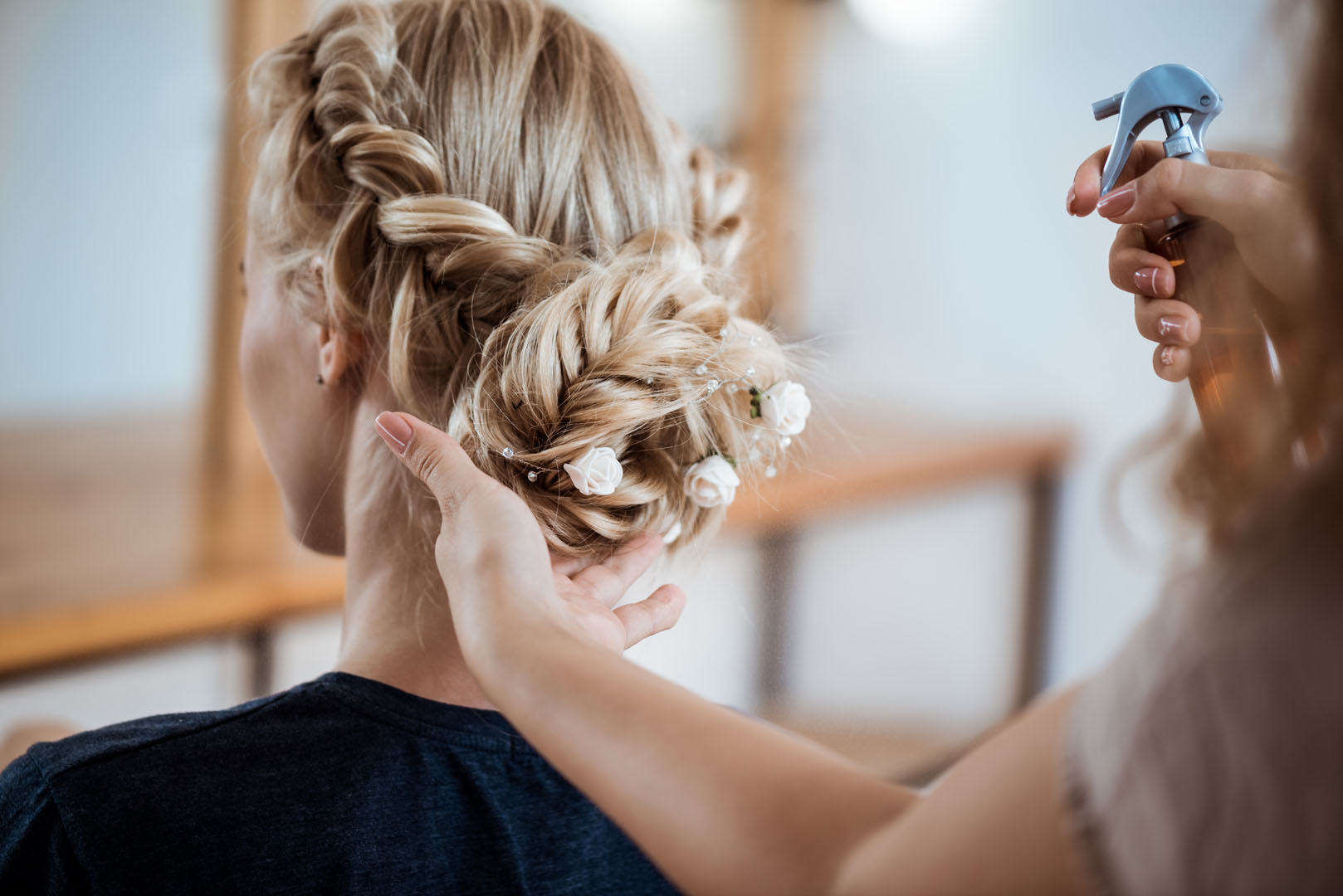 Female hairdresser making hairstyle to blonde girl in beauty salon.