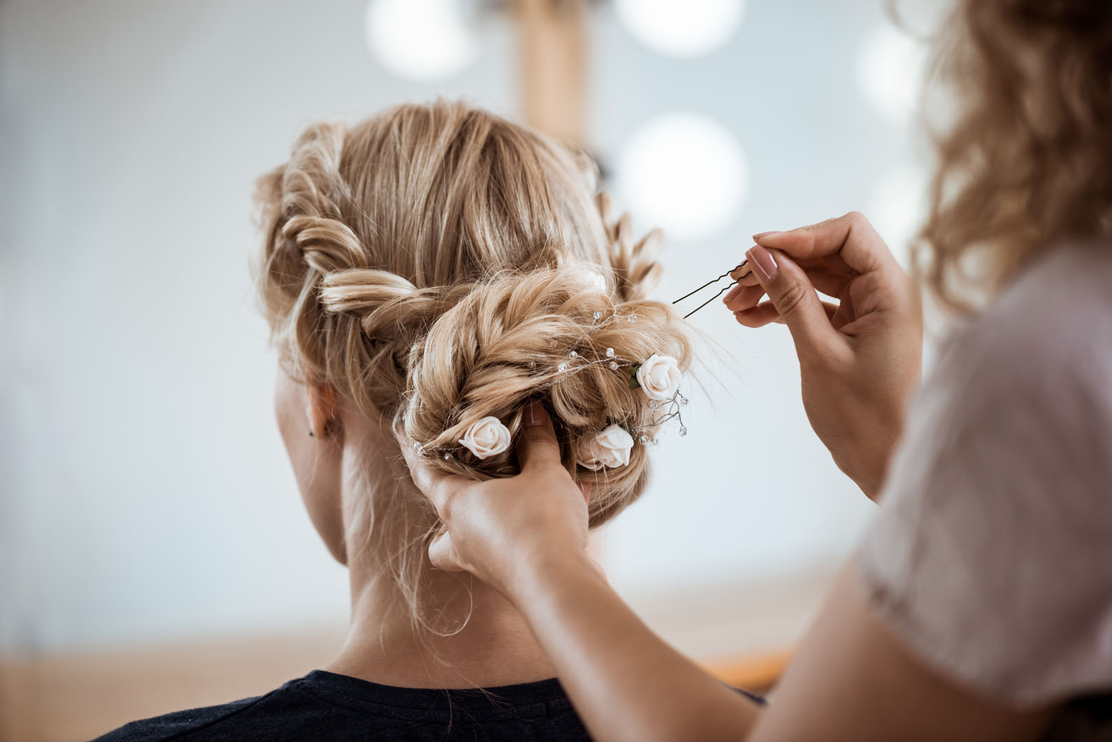 Female hairdresser making hairstyle to blonde girl in beauty salon.