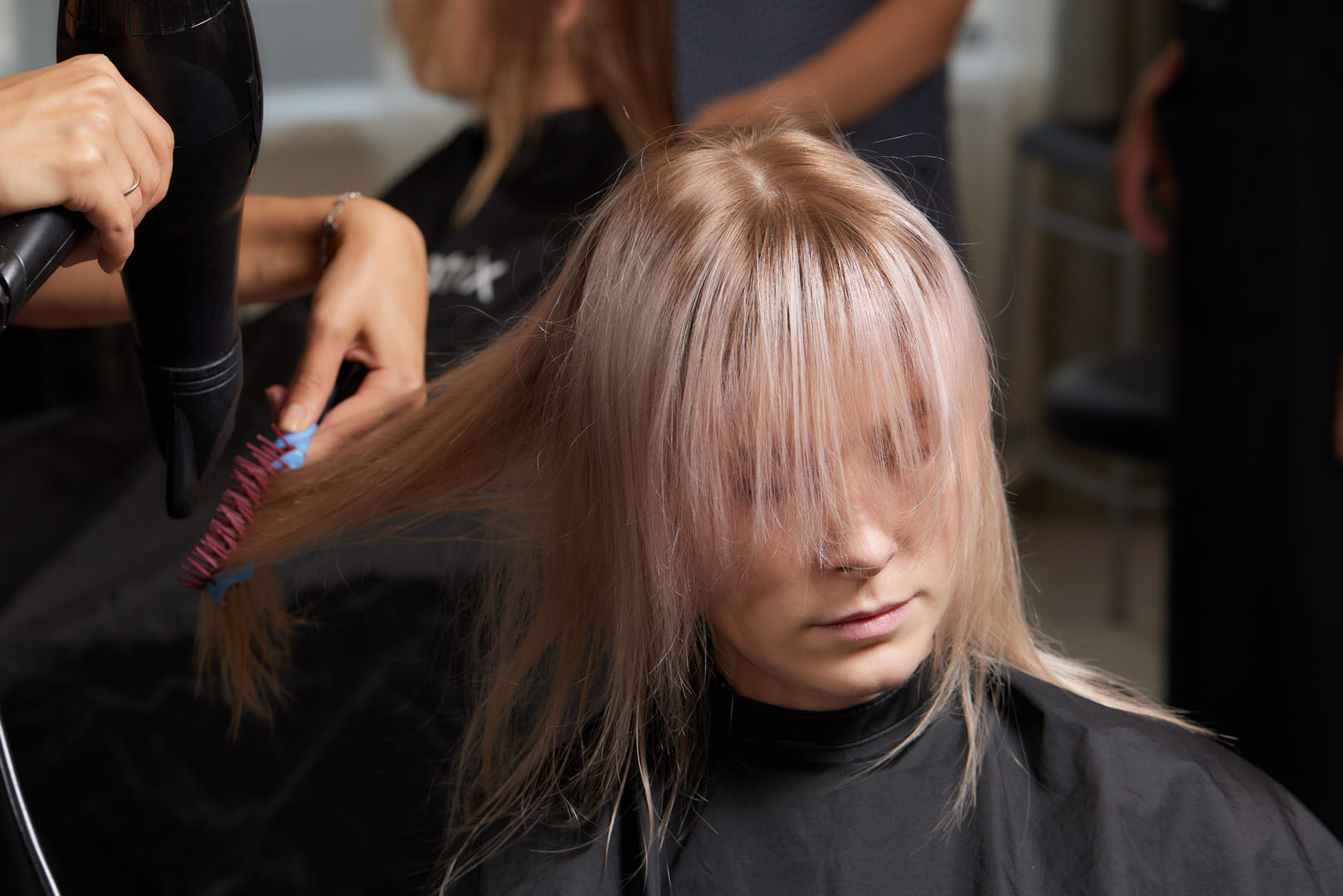 Beautiful hairstyle of young woman after dyeing hair and making highlights in hair salon.