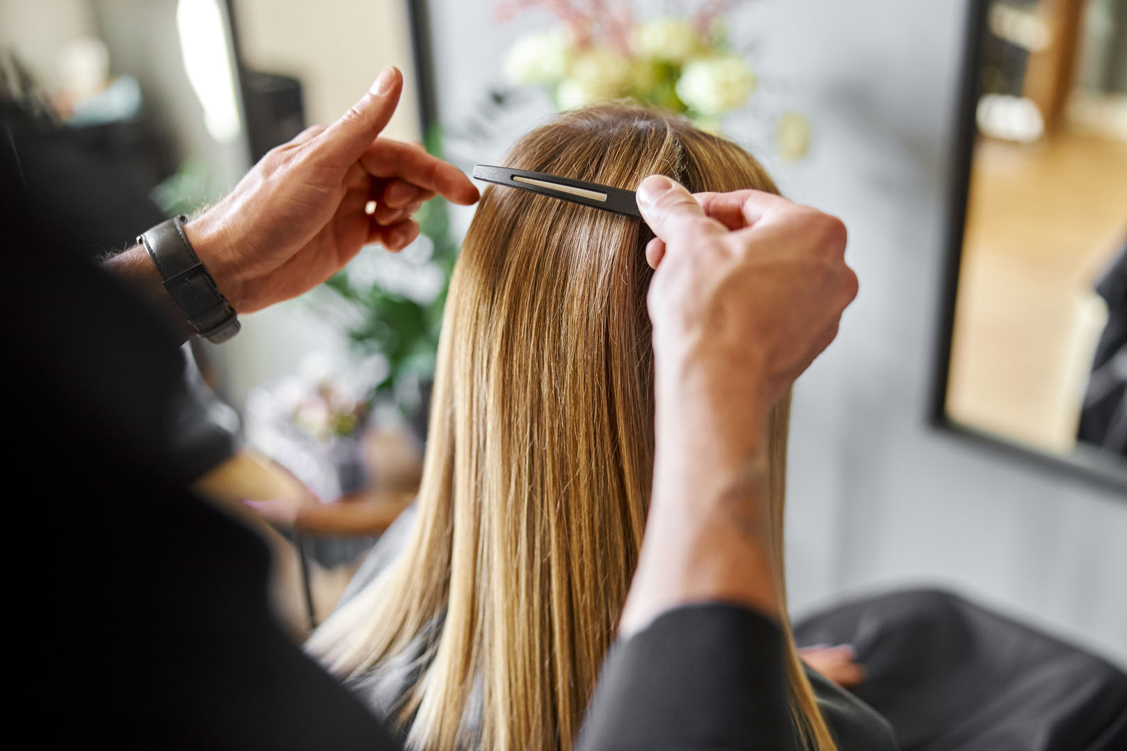 Confident male stylist is dyeing hair of blond caucasian female